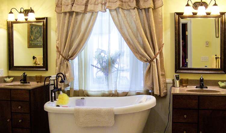 Bathroom remodel in Lake Winola, PA, featuring his and hers vanities, vaulted ceilings, arch top windows, and a freestanding bathtub.