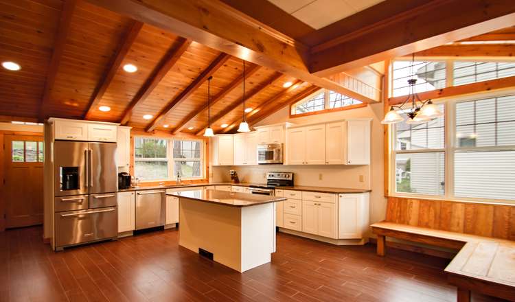 Remodeled kitchen in Lake Winola, PA, featuring exposed wood beams, ample natural light, modern white cabinets, a large island, and a cozy banquette, ideal for entertaining.