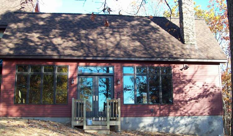 New shingle roof installation on a residential home addition in Dallas, PA, featuring a modern design with large windows and a stone chimney.