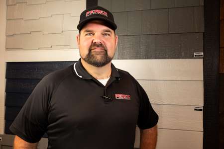 Chris Essig, Project Consultant at Perez DBR, standing in front of exterior siding samples, showcasing expertise in exterior detailing for remodeling projects.